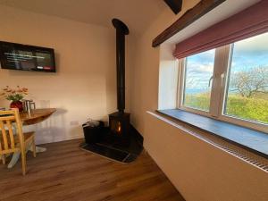 a stove in a room with a table and a window at Polrunny Farm Seaberry Cottage with a sea view and log burner in Boscastle