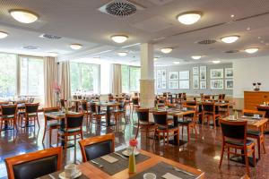 uma sala de jantar com mesas e cadeiras de madeira em Leonardo Hotel Berlin KU'DAMM em Berlim