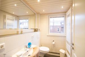 a bathroom with a toilet and a sink and a window at Haus Halligenblick Amrum in Wittdün +20 photos