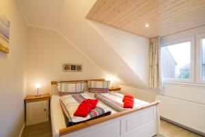 a bedroom with a bed with red pillows on it at Haus Halligenblick Amrum in Wittdün