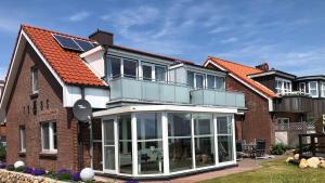 a house with a conservatory with a lot of windows at Haus Halligenblick Amrum in Wittdün