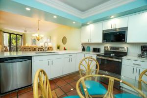 a kitchen with white cabinets and a table and chairs at Nautical Adventures in Paradise in Key West