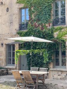 tavolo e sedie con ombrellone di fronte a un edificio di Maison Marguerite, Maison de Charme,jacuzzi a Gigny