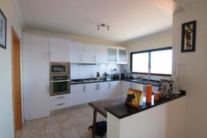 een keuken met witte kasten en een tafel. bij Casa Nici in Calheta