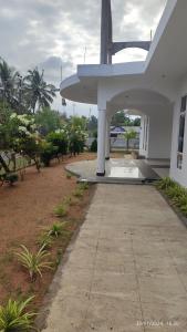 a white building with a walkway in front of it at Laxsume Guest House Nilaveli in Nilaveli