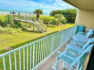 a balcony with blue chairs and a table and a beach at Beach Living at its Best! in Cocoa Beach