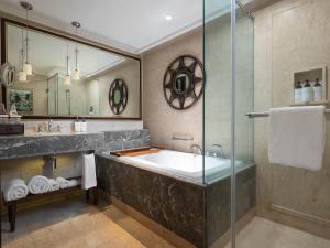 a bathroom with a tub and a glass shower at InterContinental Bali Resort by IHG in Jimbaran