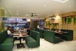 een restaurant met groene stoelen en mensen aan tafel bij Hotel Sai Krishna in Shirdi