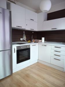 a kitchen with white cabinets and a stainless steel refrigerator at Karpos- City Mall in Skopje