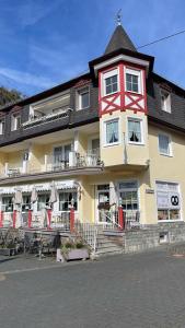 アルケンにあるCafé Bäckerei Pension Alcana Mirco Münchの黒屋根の大きな黄色と赤の建物