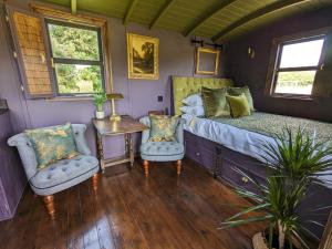a bedroom with a bed and two chairs and a table at Blue Sky Huts in Chediston