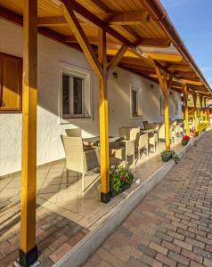 a patio with tables and chairs under a wooden pergola at Kathy Panzió in Balatongyörök