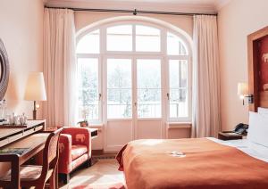 ein Hotelzimmer mit einem Bett, einem Schreibtisch und einem Fenster in der Unterkunft Schloss Elmau Luxury Spa Retreat & Cultural Hideaway in Elmau