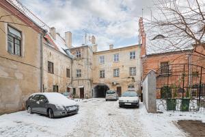 two cars parked in a snow covered street with buildings at Old town apartment with free parking by Polo Apartments in Kaunas