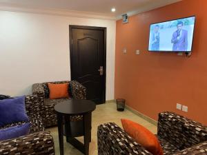 ein Wohnzimmer mit Sofas und einem TV an der Wand in der Unterkunft BOSS HOTELS & SUITES in Lagos