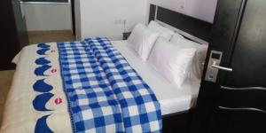 a bed with a blue and white checkered blanket on it at BOSS HOTELS & SUITES in Lagos