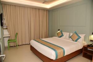 a bedroom with a large bed and a green chair at Hotel Sai Krishna in Shirdi