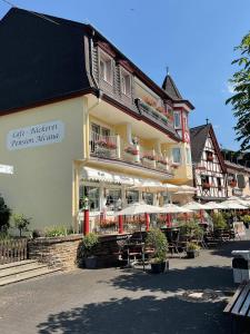 a building with tables and umbrellas in front of it at Café Bäckerei Pension Alcana Mirco Münch in Alken