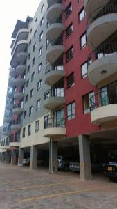 Runda Royale 3 bedroom apartment, Kiambu Road في Kiambu: مبنى احمر كبير مع شرفات في موقف للسيارات