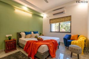 a bedroom with a bed and a chair and a window at EKOSTAY - Bliss Apartment in Candolim