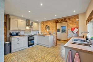 a kitchen with white cabinets and a brick wall at Finest Retreats - The Old Smithy in Belchford