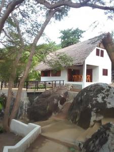 ein weißes Haus mit einem großen Felsen davor in der Unterkunft Eco Lodge Cristal Nosy Komba in Nosy Komba