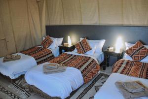 a bedroom with four beds with towels on them at Merzouga Luxury Tent in Merzouga