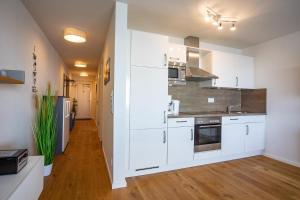 a kitchen with white cabinets and stainless steel appliances at Fewo Reeder's Nest by Seeblick Ferien ORO, 2-Zi-Hafenwohnung, Fahrstuhl in Olpenitz