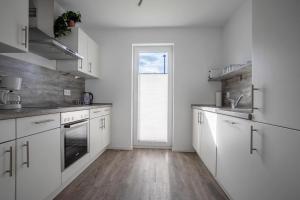 a kitchen with white cabinets and a large window at Schleivilla Lootsen Hus by Seeblick Ferien ORO, 3Etagen,8Pers,Sauna,Kamin in Olpenitz