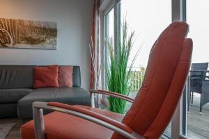 a living room with a red chair and a couch at Schleivilla Lootsen Hus by Seeblick Ferien ORO, 3Etagen,8Pers,Sauna,Kamin in Olpenitz