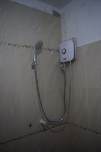 a shower in a bathroom with a hose attached to a wall at Nutmeg Tree in Katugastota
