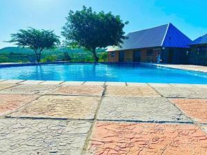 a large swimming pool with a house in the background at Inkwazi Getaway Lodge in Manzini