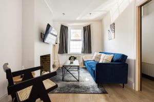 - un salon avec un canapé bleu et une fenêtre dans l'établissement The Stratford Villas, à Londres