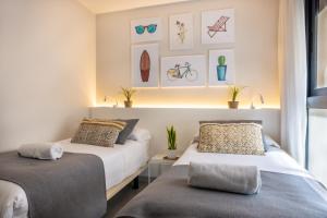 two beds in a room with pictures on the wall at Apartamentos Turísticos Puerta Real in Cartagena