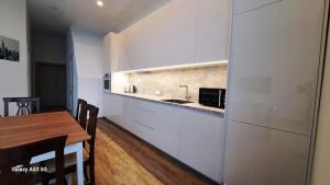 a kitchen with white cabinets and a table with a microwave at KaunasInn LA in Kaunas