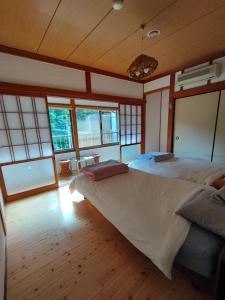 een slaapkamer met een groot bed in een kamer met ramen bij そらやまゲストハウス Sorayama guesthouse in Ino