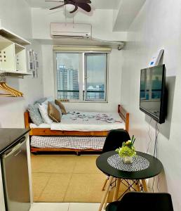 Kleines Zimmer mit einem Bett, einem Tisch und einem TV. in der Unterkunft JC Condo, SMDC Green Malate Taft Manila in Manila