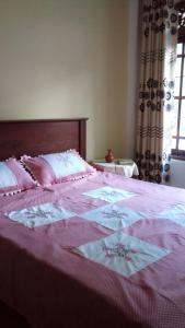 a bed with a pink and white blanket on it at Nutmeg Tree in Katugastota