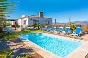 a pool with chairs and a house in the background at Casa La Vina De La Tireta in Viñuela