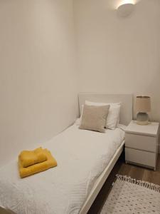 a white bed with a yellow towel on it at Brook Green 2 bed flat in London