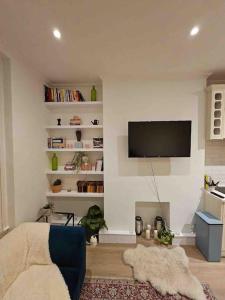 a living room with a flat screen tv on a wall at Brook Green 2 bed flat in London