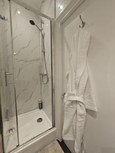 a bathroom with a shower and a white robe at Brook Green 2 bed flat in London