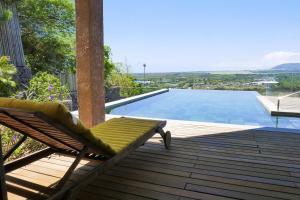 einen Stuhl auf einer Terrasse neben einem Pool in der Unterkunft Villa Teranga avec vue panoramique sur la baie de Tamarin in Tamarin