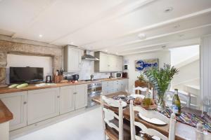 a kitchen with white cabinets and a table with chairs at Tathra Beach Cottage in St Ives