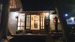 a woman standing in front of a window at night at Maliblues Bed & Art Gallery in Chumphon