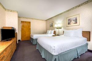 a hotel room with two beds and a flat screen tv at Days Inn by Wyndham Vineland in Vineland