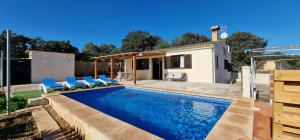 a swimming pool with blue chairs and a house at Finca con piscina rodeada de naturaleza in Sencelles
