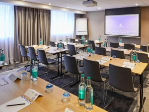 a conference room with tables and chairs and a screen at Novotel Birmingham Airport in Bickenhill