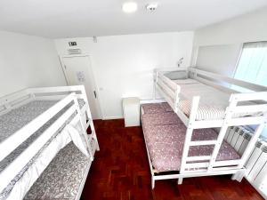 2 białe łóżka piętrowe w pokoju z drewnianą podłogą w obiekcie Hostel do Alto - Fão w mieście Esposende