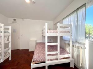 two white bunk beds in a room with a window at Hostel do Alto - Fão in Esposende